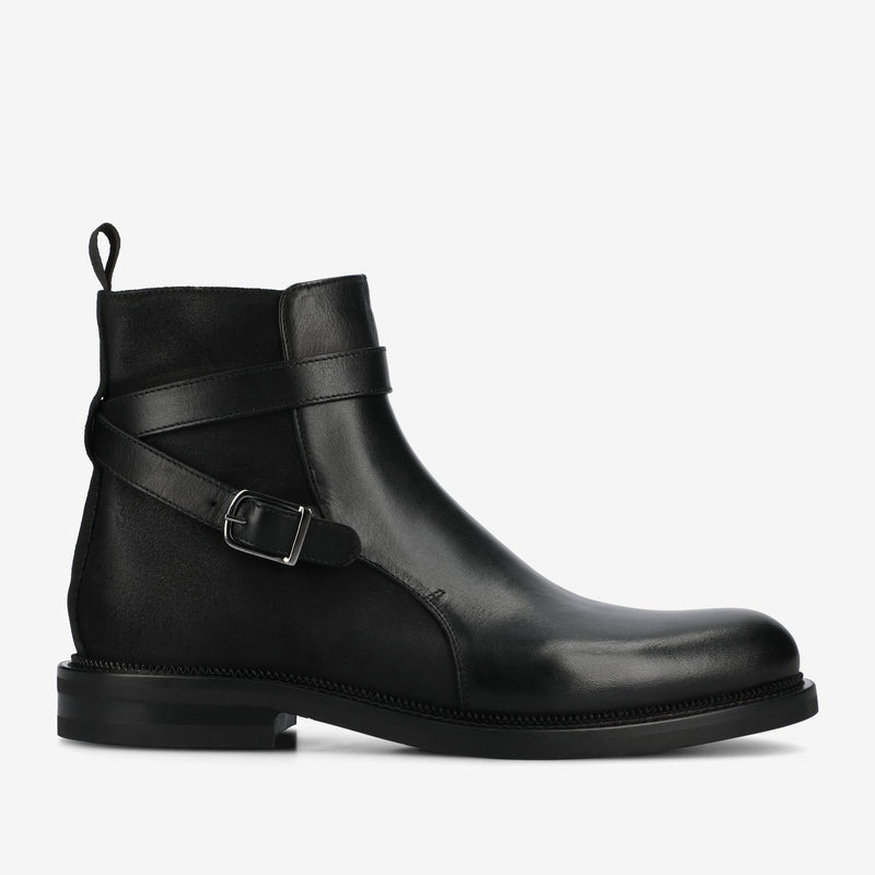 Black leather boot with a strap and buckle on a white background