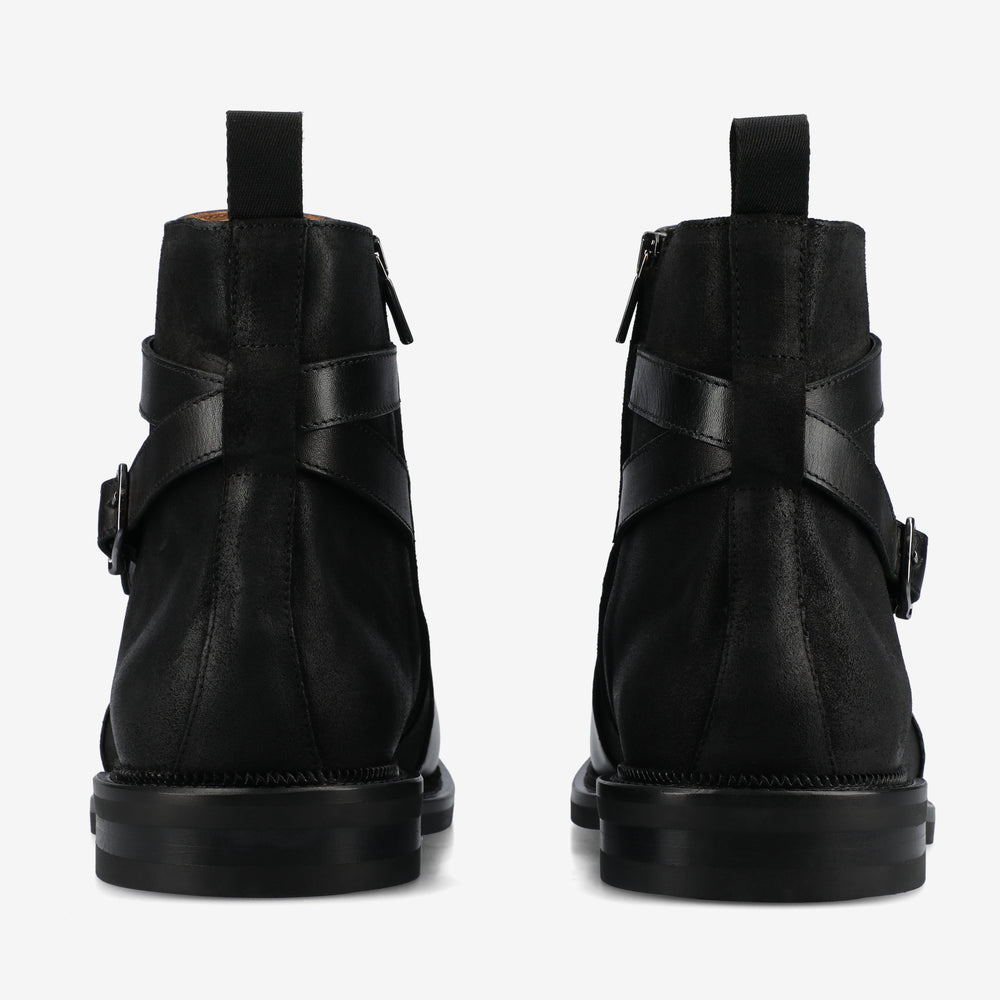 Black leather boots with buckle details on a white background