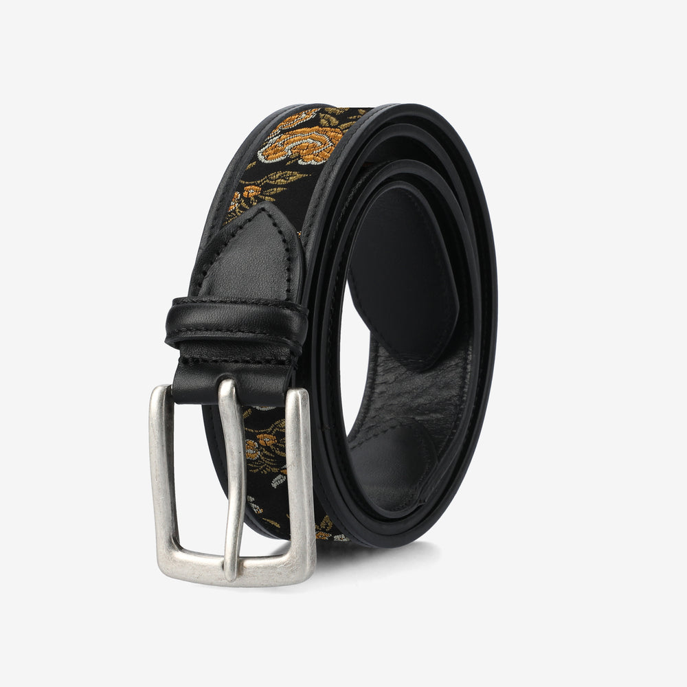 Black belt with floral pattern and silver buckle on a light gray background