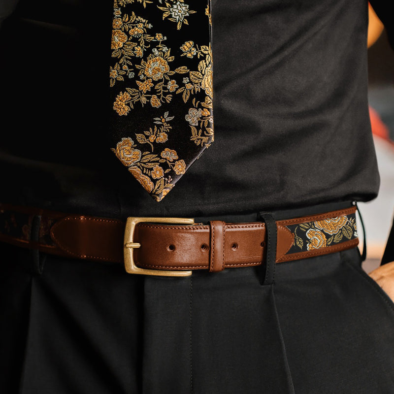 Person wearing a black shirt with a floral tie and a brown belt with floral accents. - lifestyle