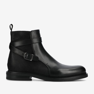 Black leather boot with a strap and buckle on a white background