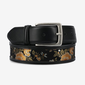 Black belt with floral embroidery and silver buckle on a light gray background