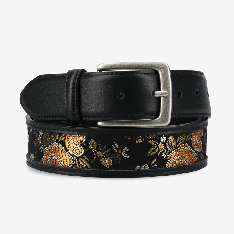 Black belt with floral embroidery and silver buckle on a light gray background