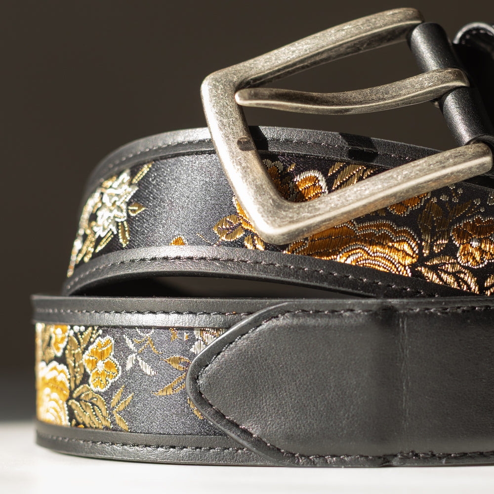 Floral patterned belt with a metallic buckle on a dark background